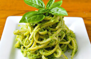 gastronomia, piatto quadrato con spaghetti al pesto e una foglia di basilico fresco sopra